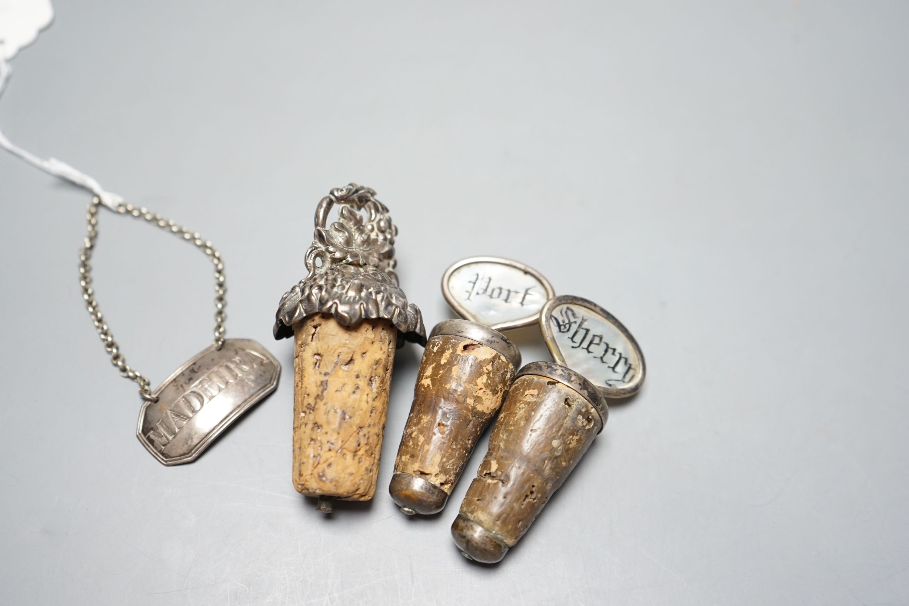 A George III silver 'Madeira' wine label, London, 1803 and three mounted cork bottle stoppers.